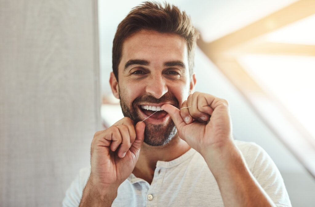 A photo of an adult using dental floss to clean their teeth.