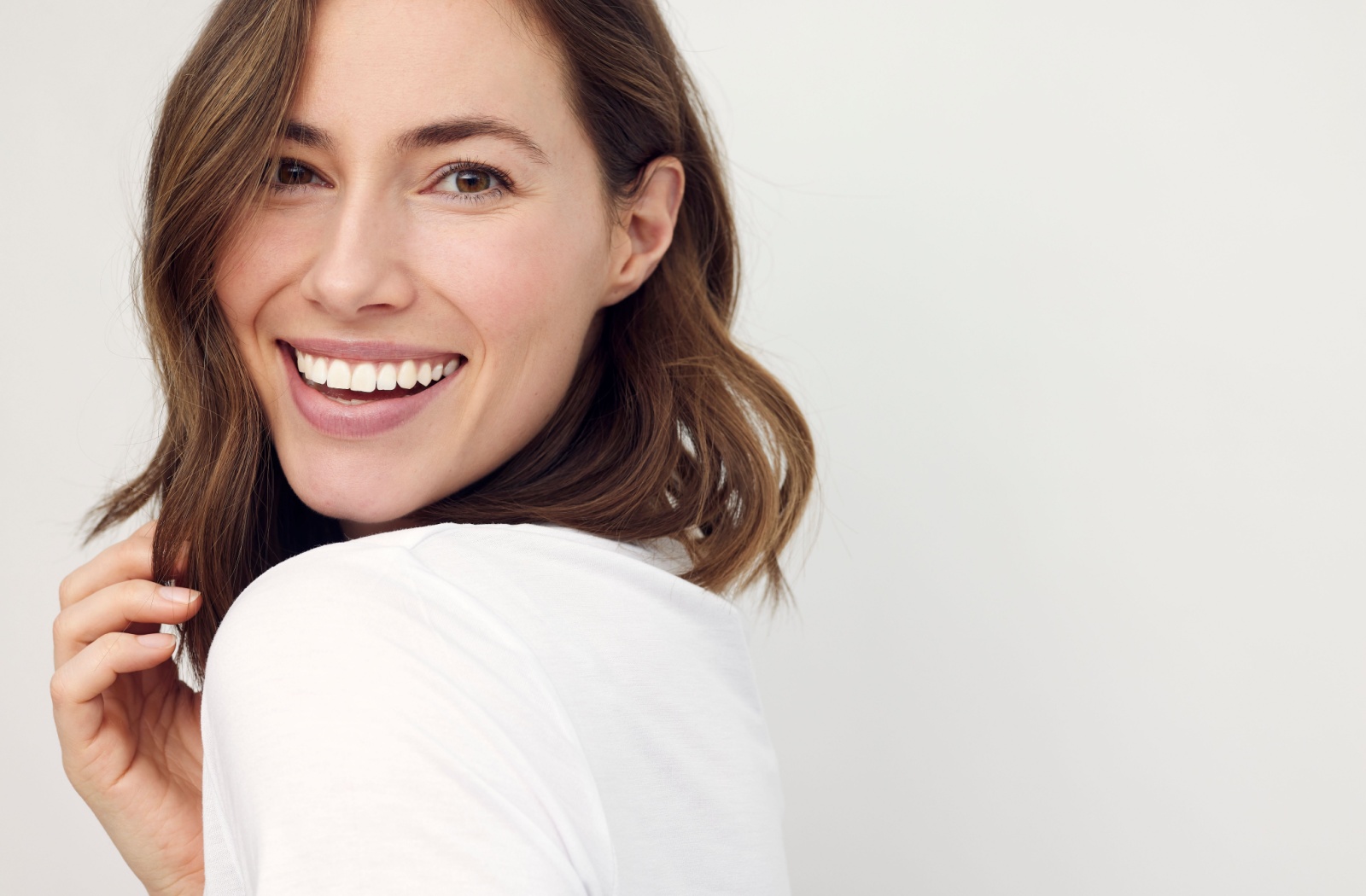 A woman, looking over her shoulder smiling.