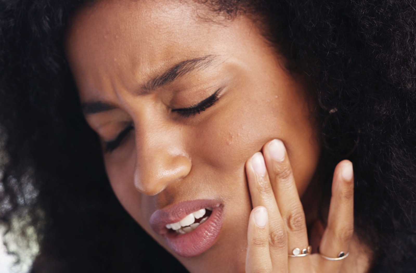 A person holding their jaw due to TMJ pain.